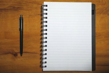 Ahşap arka planda defter ve kalem. Kopyalama alanı olan üst görünüm