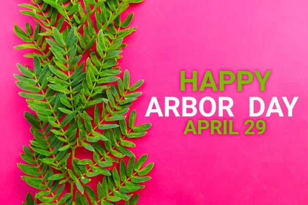 Happy Arbor Day April 29 with green leaf on pink background.