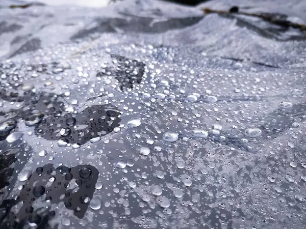 水滴在黑色塑料帆布上 自然背景 — 图库照片