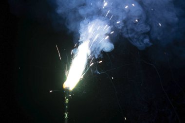 Siyah bir arkaplanda yanan kıvılcımlardan kıvılcımlar çıkıyor.