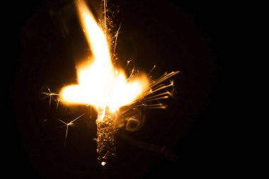 Siyah arka planda yanan maytap. Ateşten kıvılcımlar çıkıyor. Yakın plan..