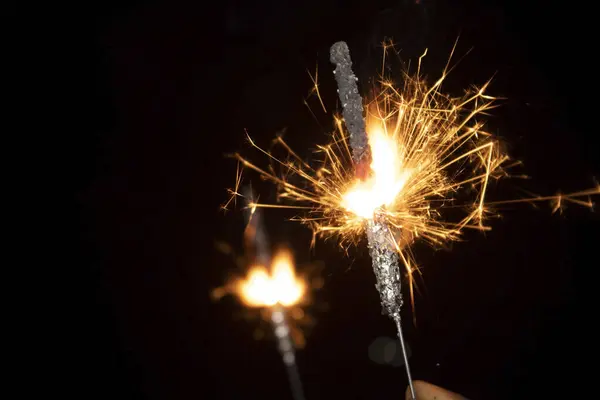Burning sparkler in hand on black background. New year and Christmas concept