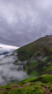 Bulutla kaplı dağ tepeleri ve yemyeşil yamaçlı Misty Highland Vadisi