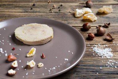 French foie gras served with nuts, pepper, salt, and dried fruits on a wooden table