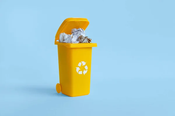 Almost closed container with paper waste isolated on the blue background with copy space, waste recycling concept