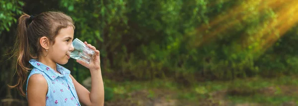 stock image Child girl drinks water from a glass. Selective focus. Kid.