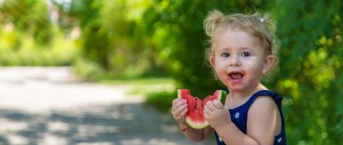 A child eats watermelon in the park. Selective focus. Kid.