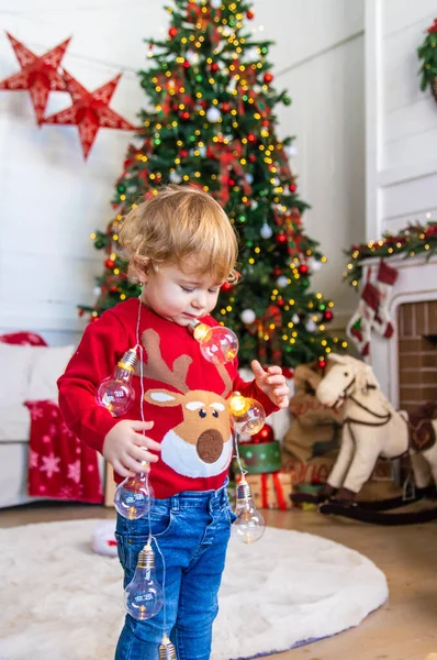 一个孩子带着花环在圣诞树前跳舞 有选择的重点 — 图库照片