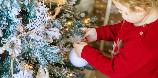 那孩子在圣诞树上挂了一个装饰品 有选择的重点 — 图库照片