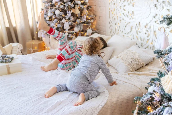 Children jump on the bed near the Christmas tree. Selective focus. kid.