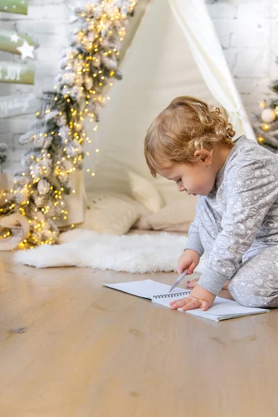 Children write a letter to Santa under the tree. Selective focus. Kid.
