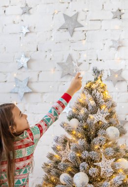 Bir çocuk Noel ağacına bir yıldız asar. Seçici odaklanma. Çocuk.