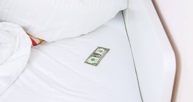 Yatağın altında bir dolar. Seçici odaklanma. Beyaz.