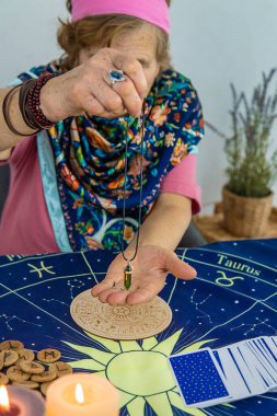 Woman fortune teller fortune telling pendulum. Selective focus. People.