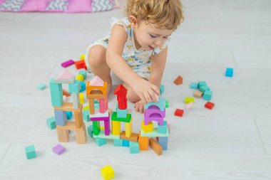 The child plays in the children's room with a wooden constructor. Selective focus. Kid.