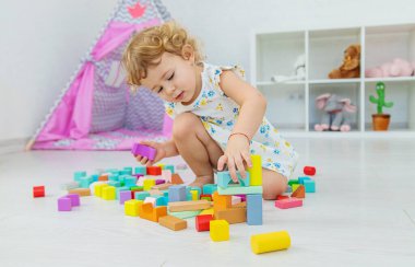 The child plays in the children's room with a wooden constructor. Selective focus. Kid.