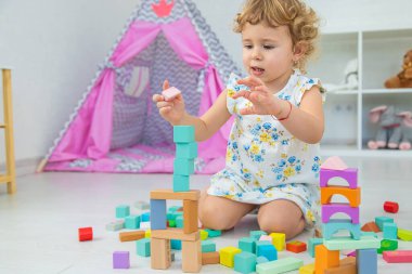The child plays in the children's room with a wooden constructor. Selective focus. Kid.