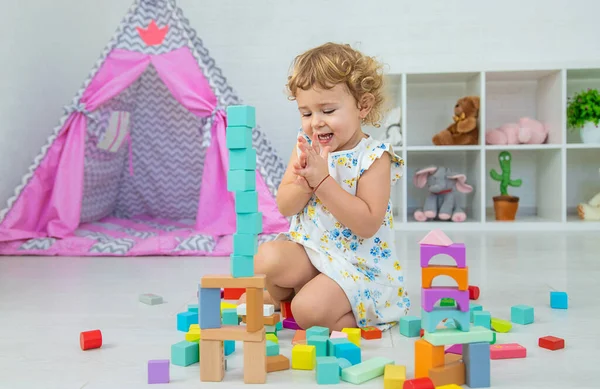 The child plays in the children's room with a wooden constructor. Selective focus. Kid.