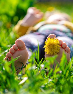 Bahar karahindiba bahçesindeki çimlerin üzerinde çocuk ayakları. Seçici odaklanma. Doğa.
