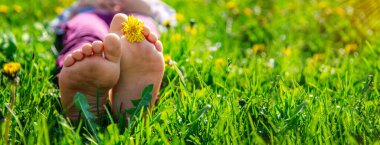 Bahar karahindiba bahçesindeki çimlerin üzerinde çocuk ayakları. Seçici odaklanma. Doğa.