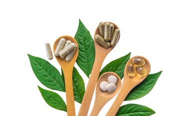 Yeşil yapraklı bitki takviyesi kapsülleri beyaz arka planda izole edilir. Seçici odaklanma. Doğa.