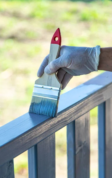 Painting a wooden board with a gray brush. Selective focus. Nature.