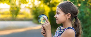 A child is studying a snail in the park. Selective focus. Nature.