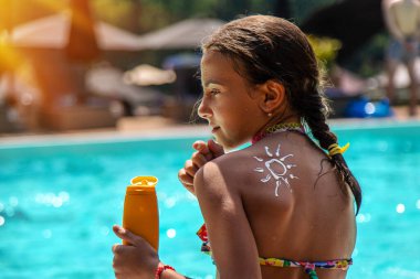 Sahilde bir çocuk sırtına güneş kremi sürüyor. Seçici odaklanma. Çocuk.