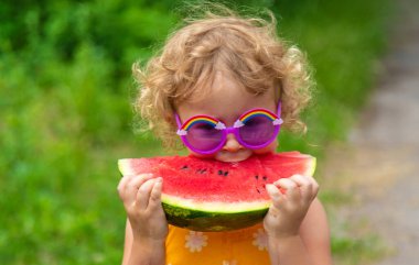 A child eats watermelon in the park. Selective focus. Kid.