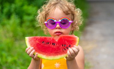 A child eats watermelon in the park. Selective focus. Kid.