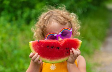A child eats watermelon in the park. Selective focus. Kid.