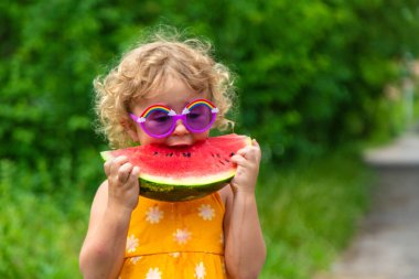 A child eats watermelon in the park. Selective focus. Kid.