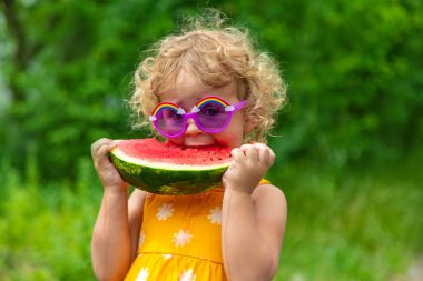 A child eats watermelon in the park. Selective focus. Kid.