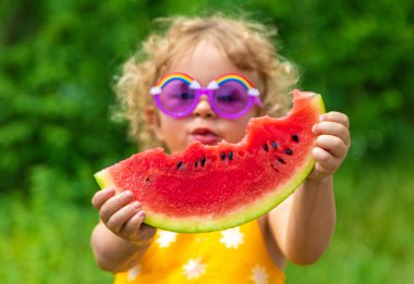 A child eats watermelon in the park. Selective focus. Kid.