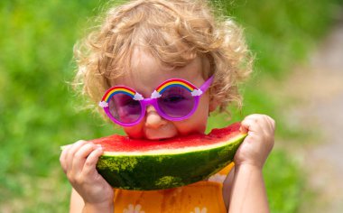A child eats watermelon in the park. Selective focus. Kid.
