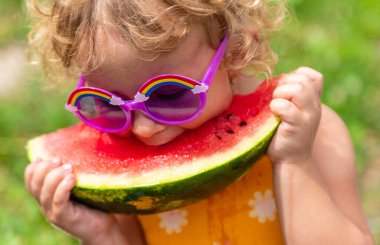 A child eats watermelon in the park. Selective focus. Kid.