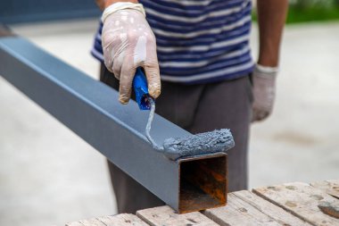 Bir adam metal bir direk boyuyor. Seçici odaklanma. Doğa.