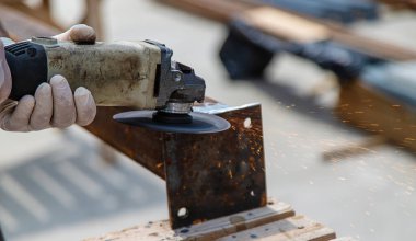 Bir adam metal bir direği işliyor. Seçici odaklanma. Doğa.