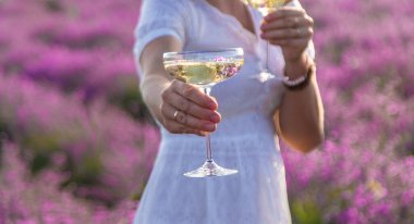 Bir kadın lavanta tarlasında şarap içiyor. Seçici odaklanma. Doğa.