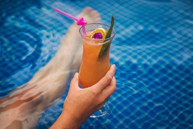 Havuzda bir kadın kokteyl içiyor. Seçici odaklanma. Çocuk.