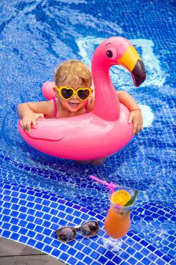 Havuzdaki bir çocuk flamingo çemberinde yüzer. Seçici odaklanma. Çocuk.