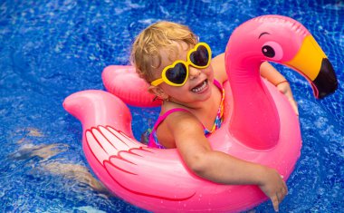 Havuzdaki bir çocuk flamingo çemberinde yüzer. Seçici odaklanma. Çocuk.