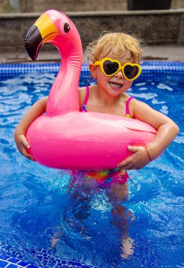 Havuzdaki bir çocuk flamingo çemberinde yüzer. Seçici odaklanma. Çocuk.