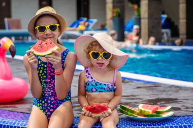 Çocuklar havuzun yanında karpuz yerler. Seçici odaklanma. Yiyecek..