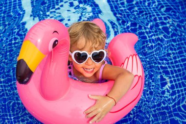 Bir çocuk flamingo çemberinde havuzda yüzer. Seçici odaklanma. Çocuk.