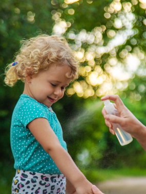 Annem çocuğuna sivrisinek kovucu sıkar. Seçici odaklanma. Doğa.