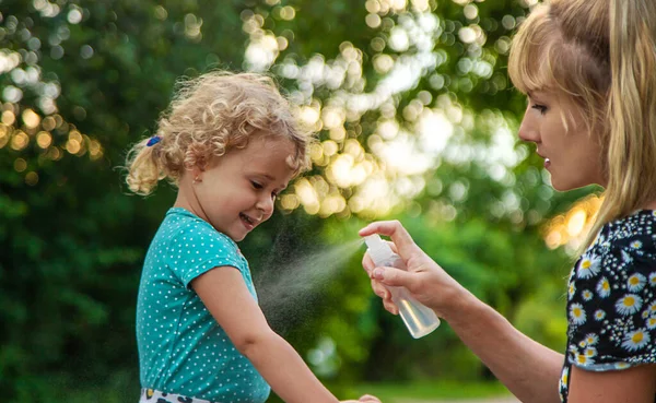 Annem çocuğuna sivrisinek kovucu sıkar. Seçici odaklanma. Doğa.
