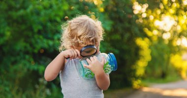 Bir çocuk elinde büyüteçle kavanoza bakar. Seçici odaklanma. Çocuk.