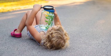 Bir çocuk elinde büyüteçle kavanoza bakar. Seçici odaklanma. Çocuk.