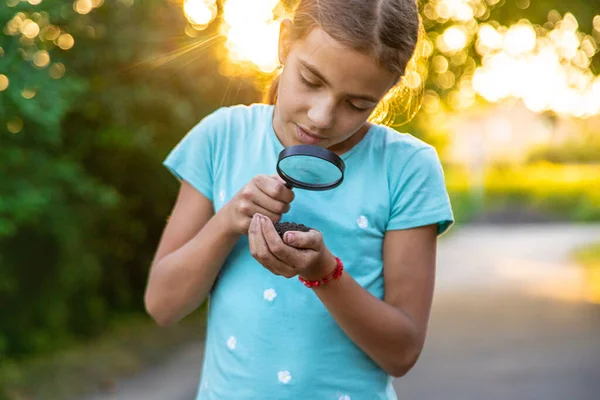 Çocuk bir büyüteçle ellerindeki toprağa bakıyor. Seçici odaklanma. Çocuk,
